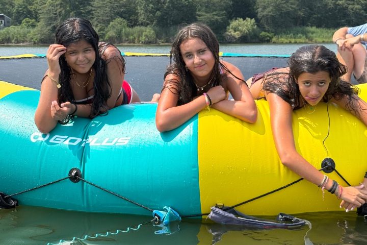 Three people on a yellow and blue inflatable raft on a lake.