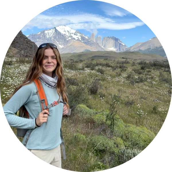 Woman hiking with mountains and wildflowers in the background.
